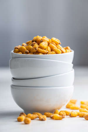 Roasted salted corn snack in bowl on a white table.