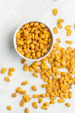 Roasted salted corn snack in bowl on a white table. Top view.