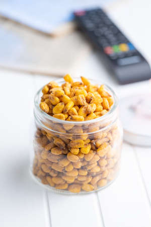 Roasted salted corn snack in jar on a white table.