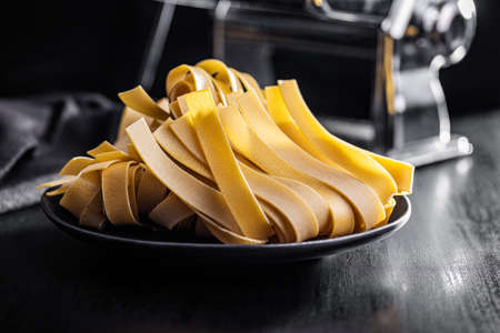 Uncooked pappardelle pasta on a plate on a black table.の写真素材
