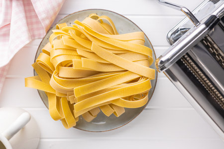 Uncooked pappardelle pasta on a plate on a white table. Top view.の写真素材