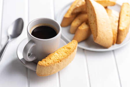 Sweet anicini cookies and coffee cup. Italian biscotti with anise flavor on a white table.