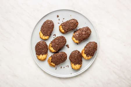 Petit fours with chocolate sprinkles on kitchen table. Mini chocolate dessert on a plate. Top view.の写真素材