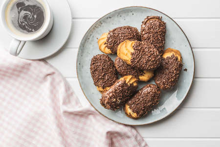 Petit fours with chocolate sprinkles. Mini chocolate dessert and a coffee cup. Top view.