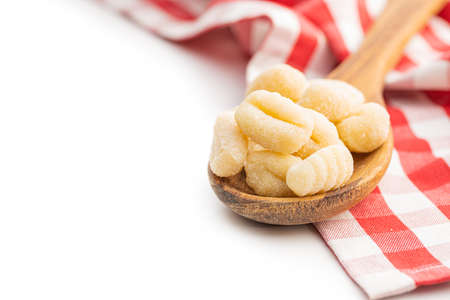 Uncooked potato gnocchi in wooden spoon isolated on a white background.の写真素材