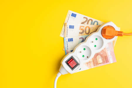 Electric socket and euro money on the yellow background. Concept of increasing electric prices. Top view.の写真素材