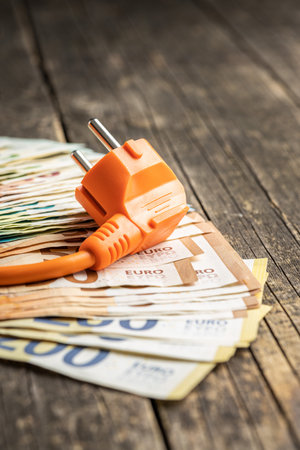 Electric plug and euro money on the wooden table. Concept of increasing electric prices.の写真素材