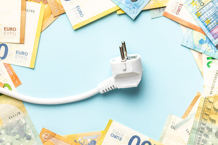 Electric plug and euro money on the blue background. Concept of increasing electric prices. Top view.の写真素材