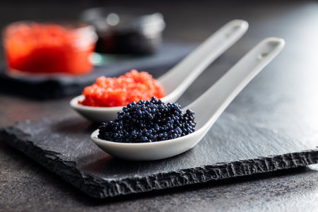 Red and black caviar in ceramic spoon on the dark table.の写真素材
