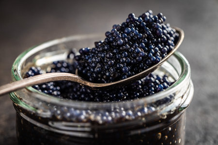 Black caviar in silver spoon on the dark table.