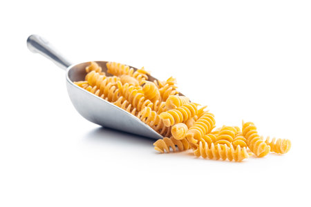 Uncooked whole grain pasta isolated on white background. Raw pasta in the scoop.の写真素材