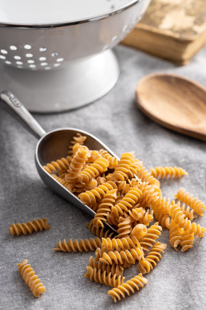 Uncooked whole grain pasta. Raw penne pasta in the scoop.の写真素材