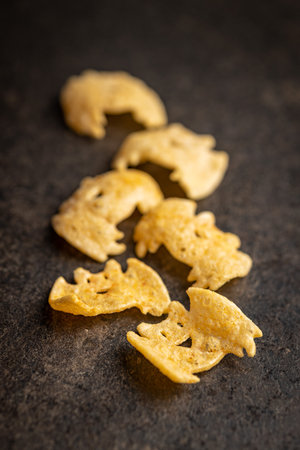 Halloween crispy bat shaped chips on the dark table.