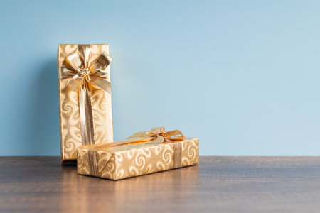 Two gold gifts on the table before the blue wall.の写真素材