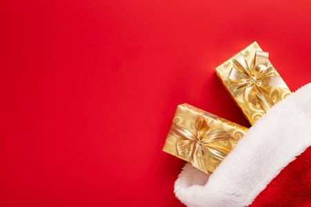 Gold christmas gift in red Santa hat on the red background. Top view.の写真素材