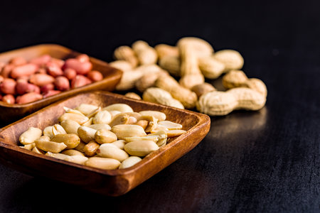 Unpeeled and peeled peanuts in a bowl on the kitchen table.