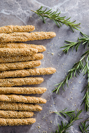 Italian grissini bread sticks with sesame seeds and rosemary on the kitchen table. Top view.の写真素材