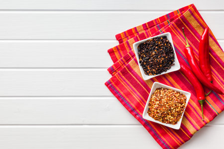 Dry chili pepper flakes. Crushed red peppers in a bowl on the white table. Top view.の写真素材