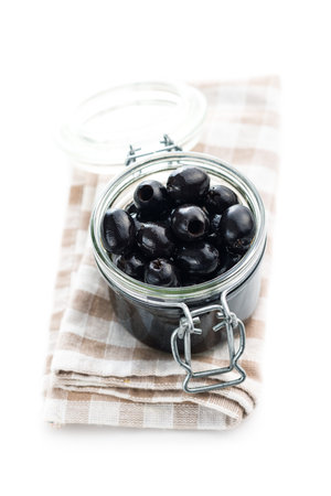 Pitted black olives in jar isolated on white background.の写真素材