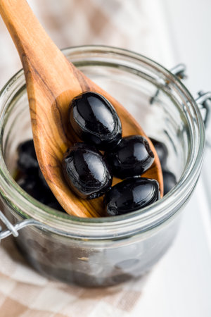 Pitted black olives in the wooden spoon.の写真素材