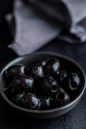 Pitted black olives in a bowl on the kitchen table.の写真素材