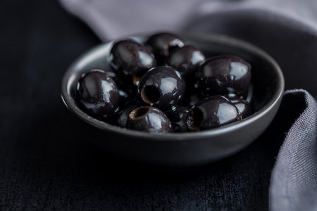 Pitted black olives in a bowl on the kitchen table.の写真素材