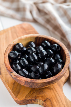Pitted black olives in wooden bowl on the kitchen table.の写真素材