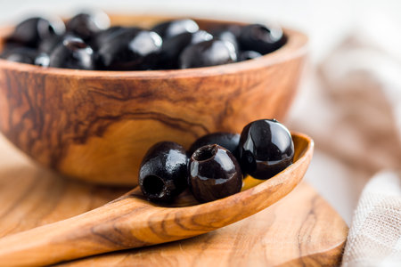 Pitted black olives in the wooden spoon.の写真素材