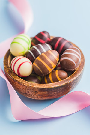 Chocolate easter eggs in a bowl on the blue background.の写真素材