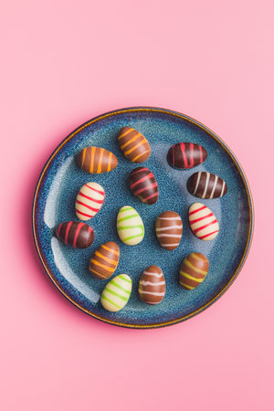 Chocolate easter eggs on a plate on the pink background. Top view.の写真素材