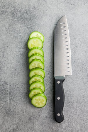Sliced fresh green cucumber and knife on the kitchen table. Top view.の写真素材