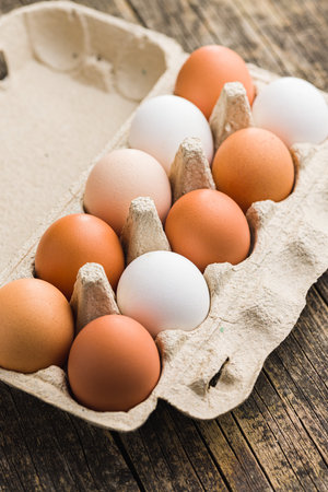 Whole chicken eggs in eggbox on the wooden table.の写真素材