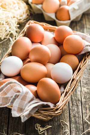 Whole chicken eggs in basket on the wooden table.の写真素材