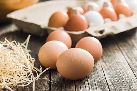Whole chicken eggs on the wooden table.の写真素材