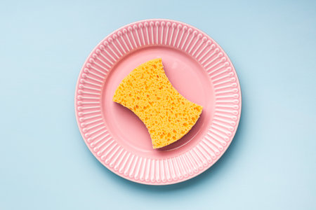 Sponge for washing dishes on the plate on a blue background. Top view.の写真素材