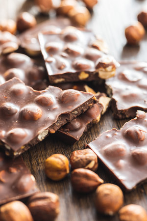 Broken chocolate bars with nuts on the wooden table.の写真素材