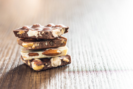Broken chocolate bars with nuts on the wooden table.の写真素材