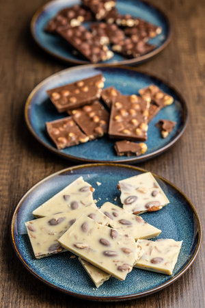 Broken chocolate bars with nuts on the wooden table.の写真素材