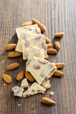 White broken chocolate bars with almonds on the wooden table.の写真素材