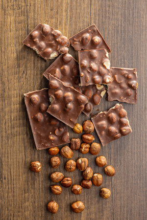 Broken chocolate bars with nuts on the wooden table. Top view.の写真素材