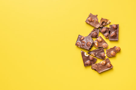 Chocolate bars with nuts on the yellow background. Top view.の写真素材