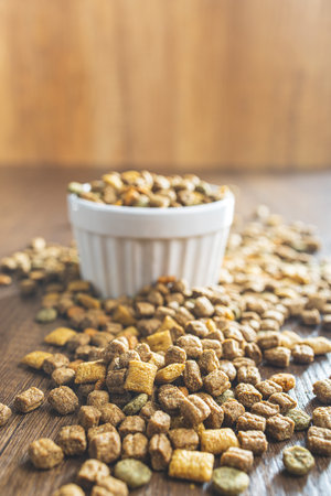 Dry kibble pet food. Dog or cat food in bowl on the wooden table.の写真素材