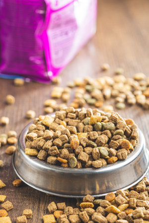 Dry kibble pet food. Dog or cat food in bowl on the wooden table.の写真素材