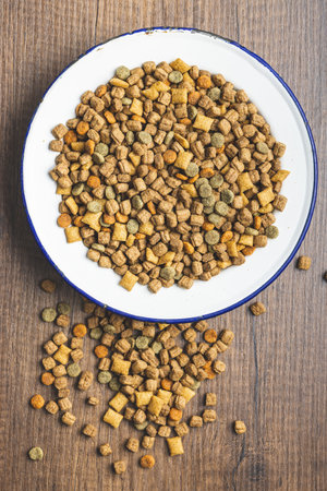 Dry kibble pet food. Dog or cat food in bowl on the wooden table. Top view.の写真素材