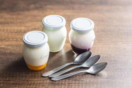 White and fruit yogurt in a jar on the wooden table.の写真素材