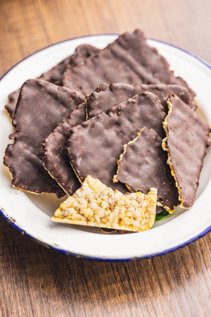 Puffed corn crackers chocolate covered on the wooden table.の写真素材
