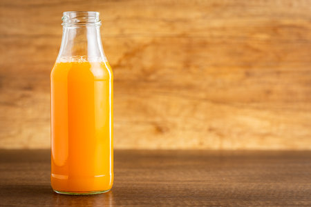 A glass bottle of fruit juice. Orange juice on the wooden table.の写真素材