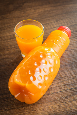 A bottle of fruit juice. Orange juice on the wooden table.の写真素材