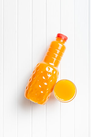 A plastic bottle of fruit juice. Orange juice on the white table. Top view.の写真素材