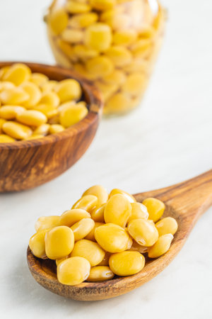 Lupini beans in brine. Pickled lupin on wooden spoon on the kitchen table.の写真素材